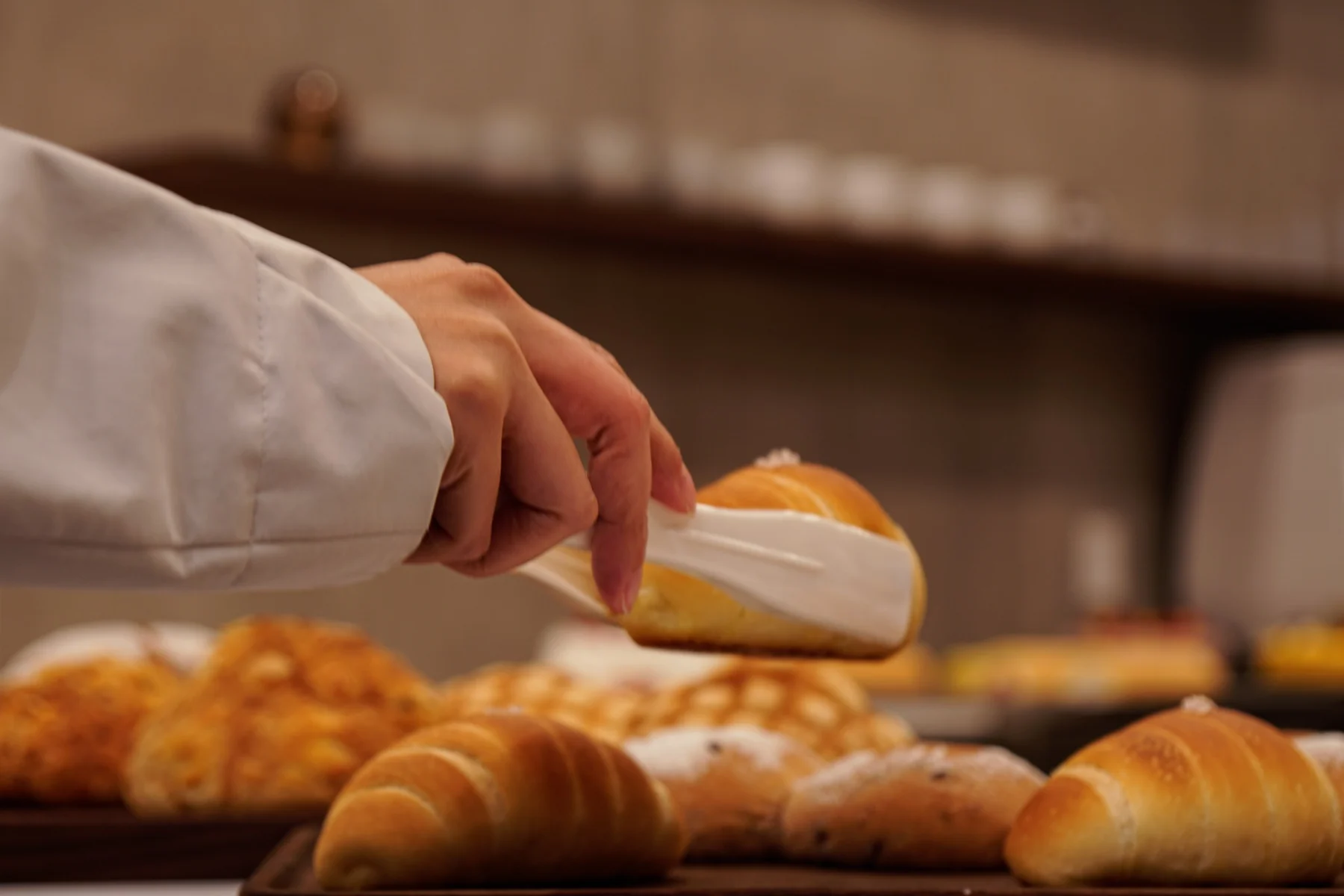 A baker brushing the tops of golden buns