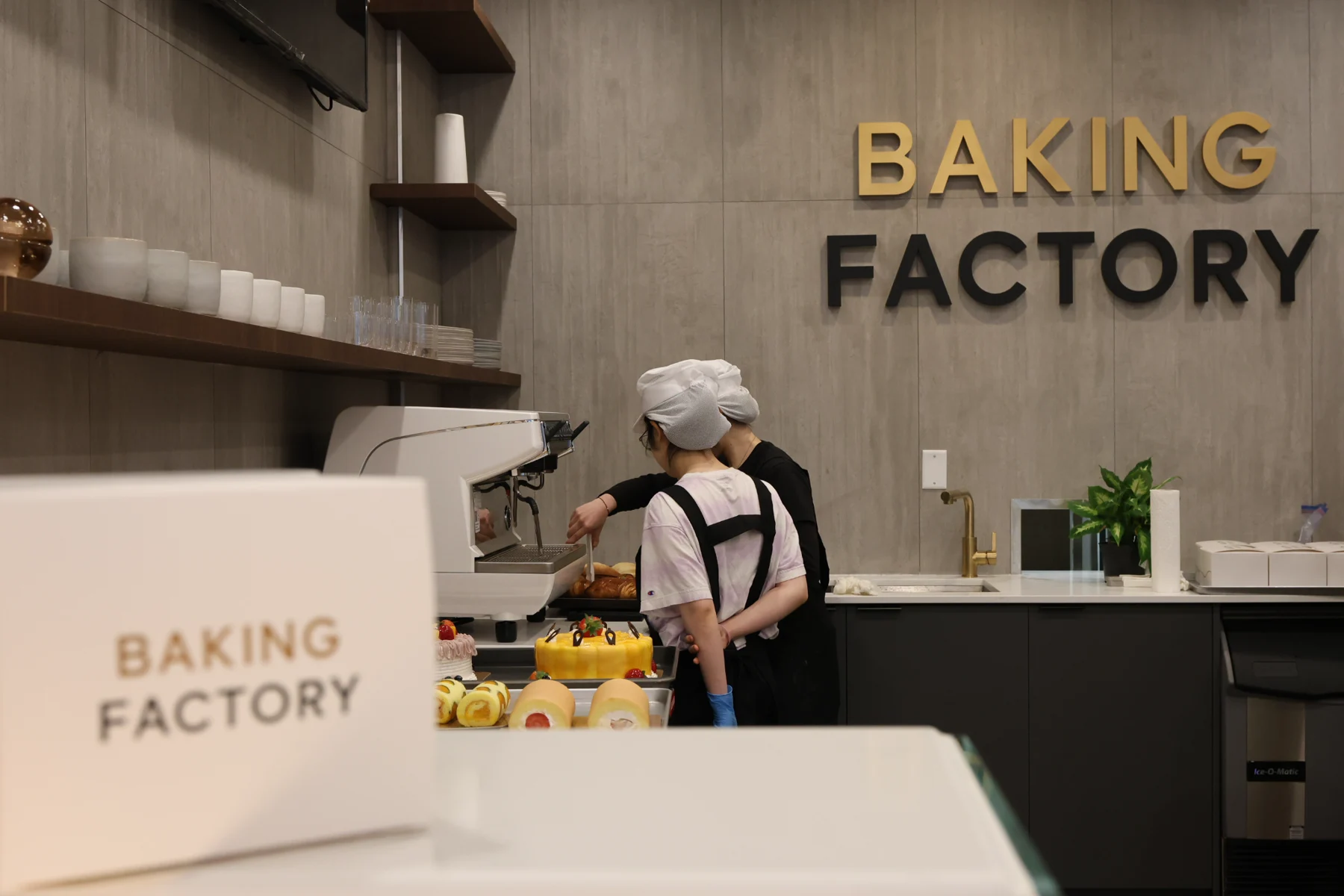 A team member behind the counter beneath Baking Factory signage